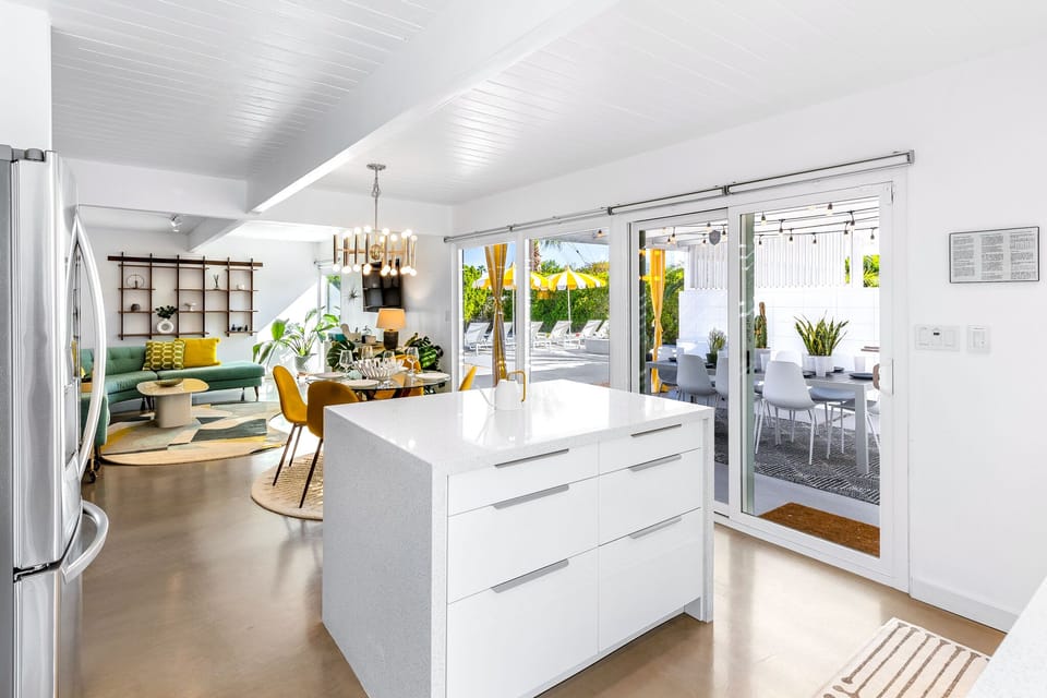Open concept kitchen, living and dining with walls of glass looking out at the pool