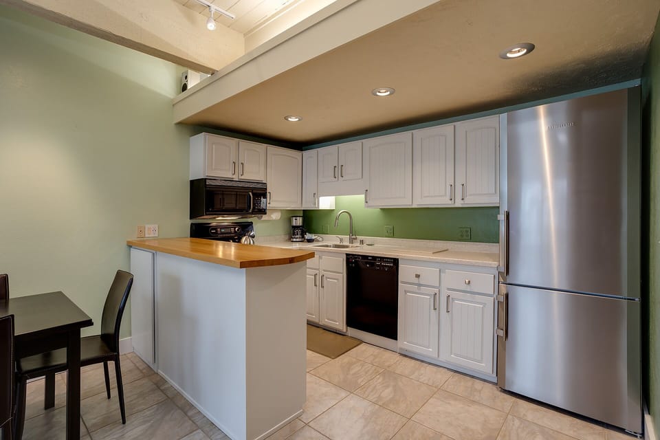 Your fully-equipped kitchen features modern stainless steel appliances and a breakfast bar perfect for morning coffee conversations.
