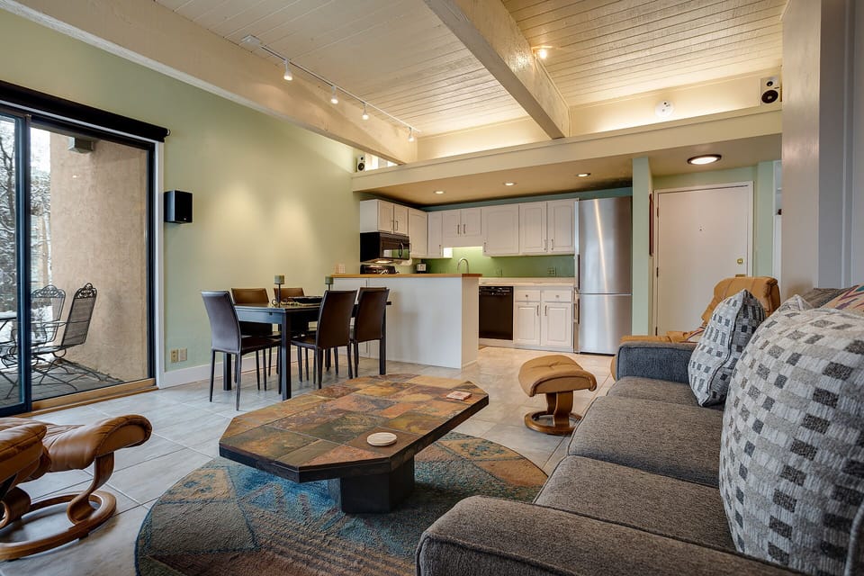 Your open-concept living space features vaulted wood ceilings and sleek modern furnishings that create the perfect atmosphere for relaxing after mountain adventures.