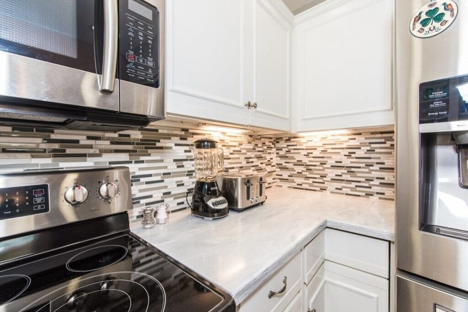 Modern kitchen with stainless steel appliances and chic backsplash.