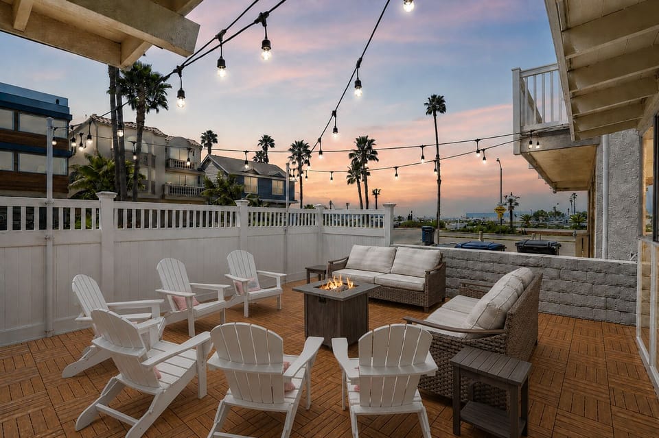 Secure and stylish front patio with lounge seating, a gas fire pit, and string lights—perfect for unwinding after the beach.