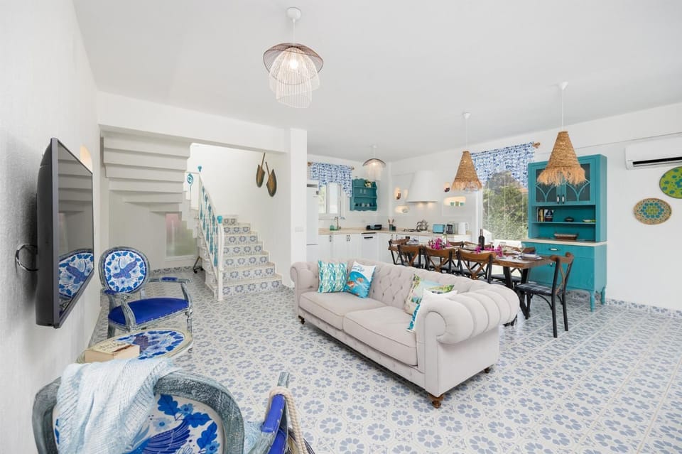 Open-plan living room with sofa, dining area, kitchen, A/C, WiFi internet, and satellite TV