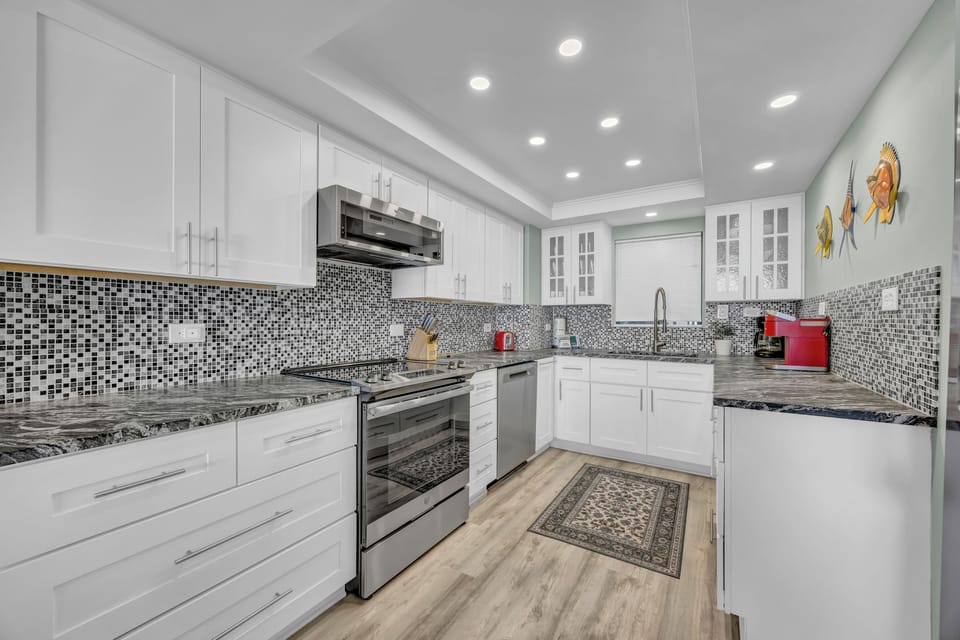 Step into this sleek, fully-equipped kitchen where you'll find everything you need: stylish mosaic tile backsplash, stainless steel appliances, and plenty of counter space for your culinary creations.