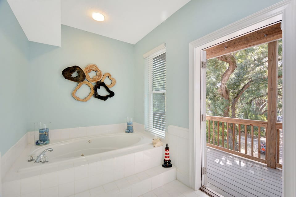 Jacuzzi Tub + Balcony View – King Suite Bathroom - Soak in the jacuzzi tub while gazing out toward the treetops. This spa-style primary bath blends comfort and calm inside one of St. Simons Island’s most relaxing vacation rentals.