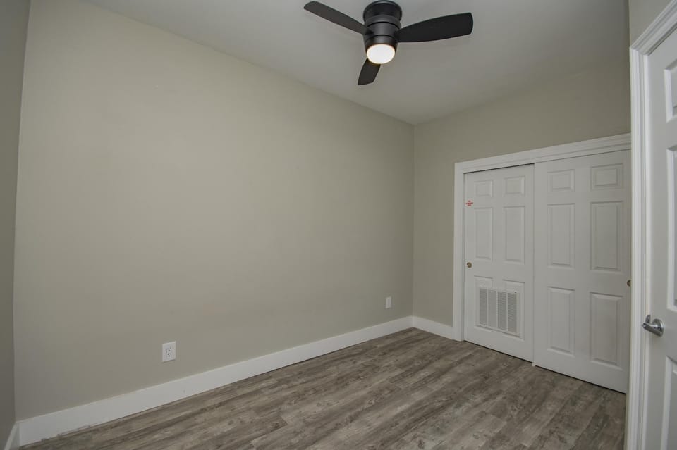Cozy bedroom retreat with modern ceiling fan and wood floors