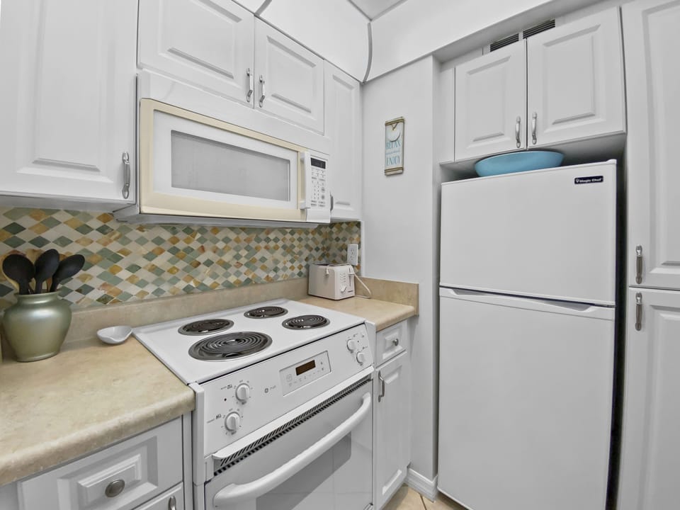 Kitchen alt angle showing white cabinets, mosaic backsplash, and full-size appliances