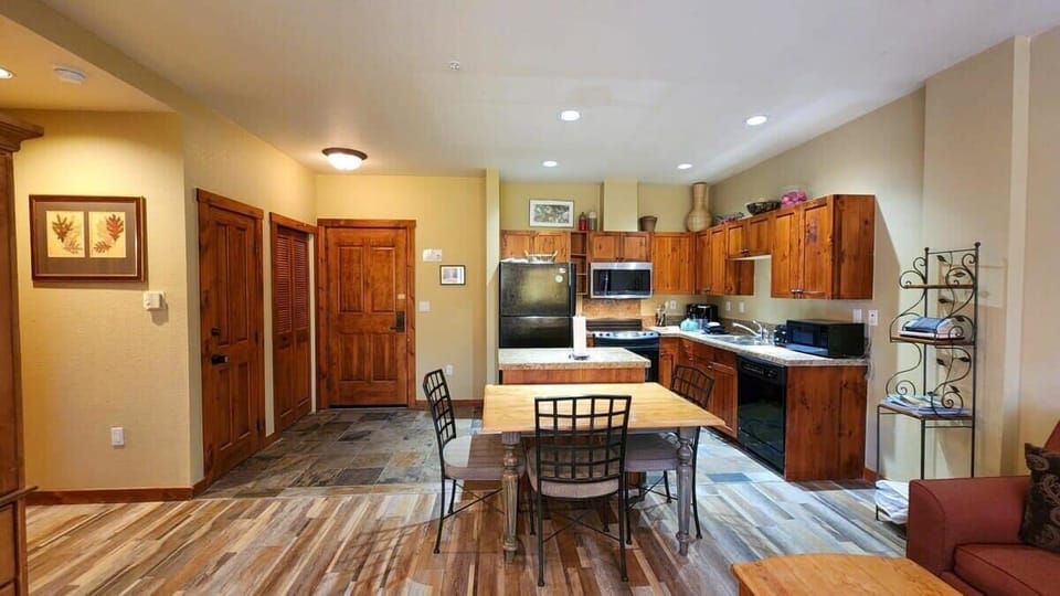 The view into the kitchen and dining room from the living room where you will find a fully stocked kitchen complete with an island space great for additional room for food prep and a dining table with seating for 6.