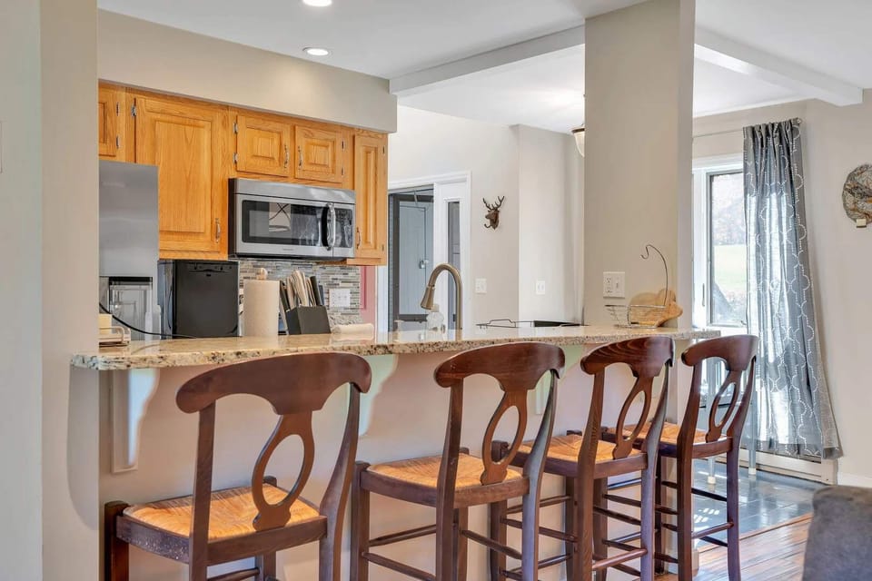 Granite breakfast bar with four rustic wooden stools, perfect for casual meals