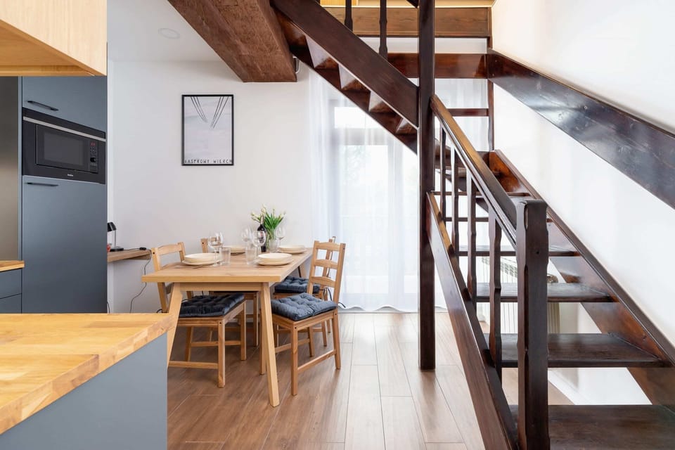 A dining area with a wooden staircase leading to an upper level, surrounded by rustic decor.
