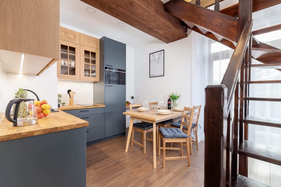 A modern kitchen with wooden beams and a dining table adorned with fresh flowers.
