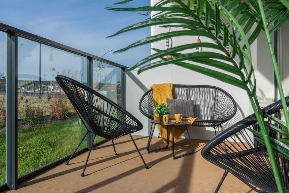 A balcony with comfortable seating and vibrant greenery.

