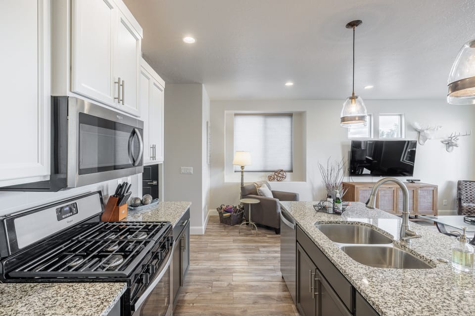 Kitchen Side View - The kitchen is fully stocked with all the dishes, cookware, baking pans, and cutlery you will need for meal preparations and includes stainless steel appliances and granite counter tops.