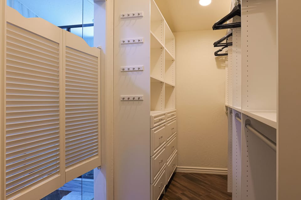 Large walk-in closet with wooden hangers and built-in drawers. (Bathroom 4)