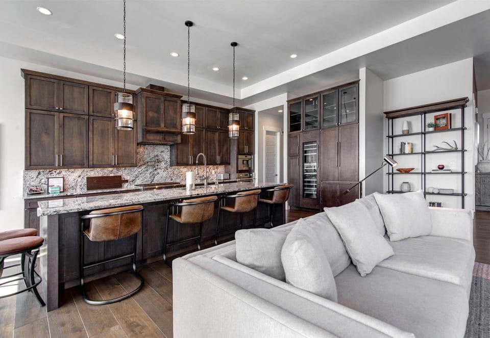 Sink into your couch and savor the open-concept elegance—rich wood cabinetry, granite countertops, and pendant lighting create a chef's dream kitchen flowing seamlessly into your living space.