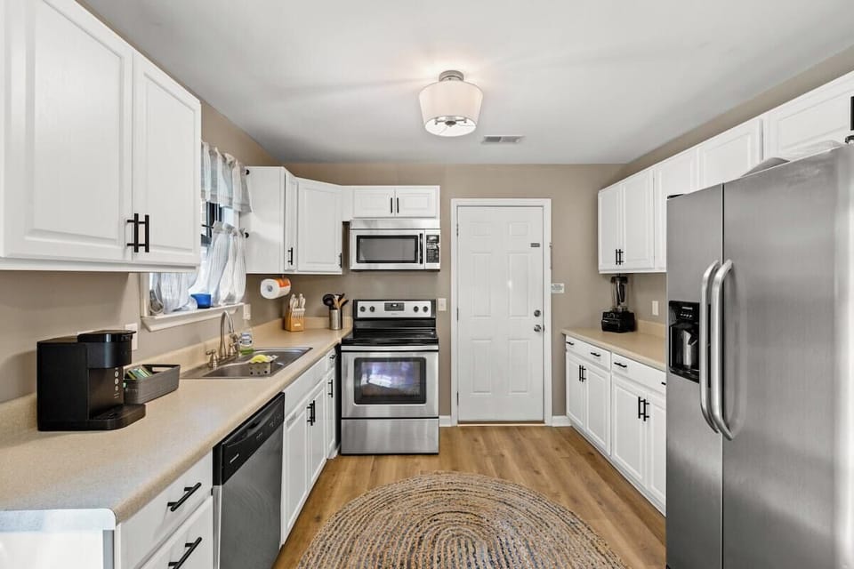 Full sized kitchen stocked with cups, coffee mugs, cooking utensils, silverware and service for 6.