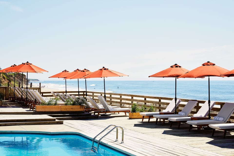 Lounge oceanfront under vibrant umbrellas, listening to waves.
