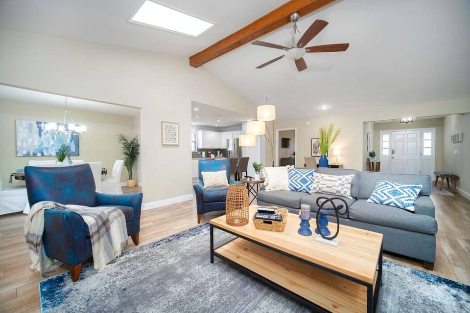 Open-concept living area with stylish seating, skylights, and seamless flow to dining and kitchen.
