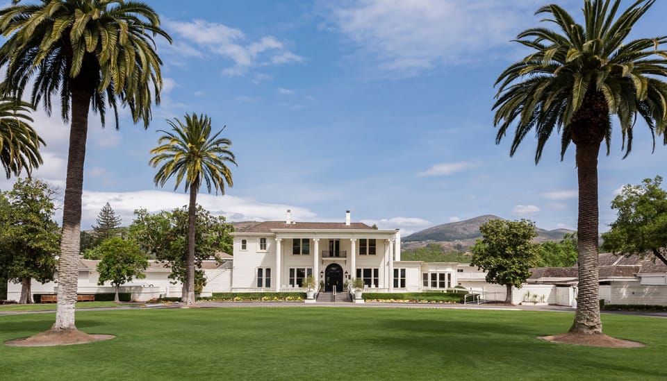 Arrive to a grand estate framed by palms and lawns.