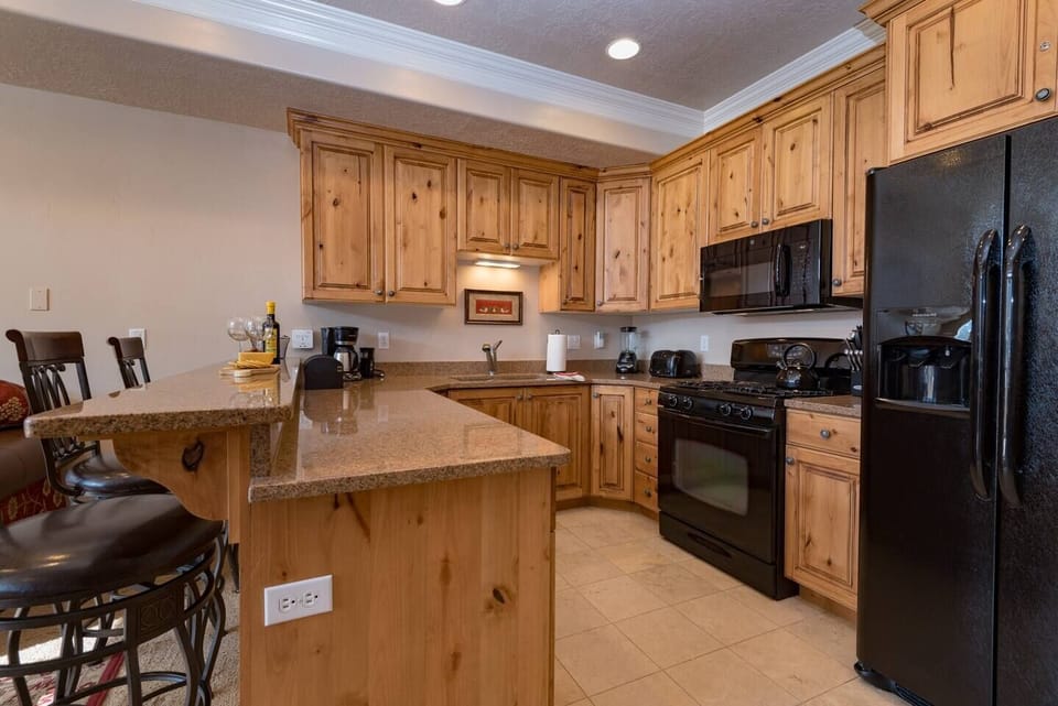 The gourmet kitchen features an island with seating for three and is equipped with appliances, including a microwave, gas stove, and spacious refrigerator.