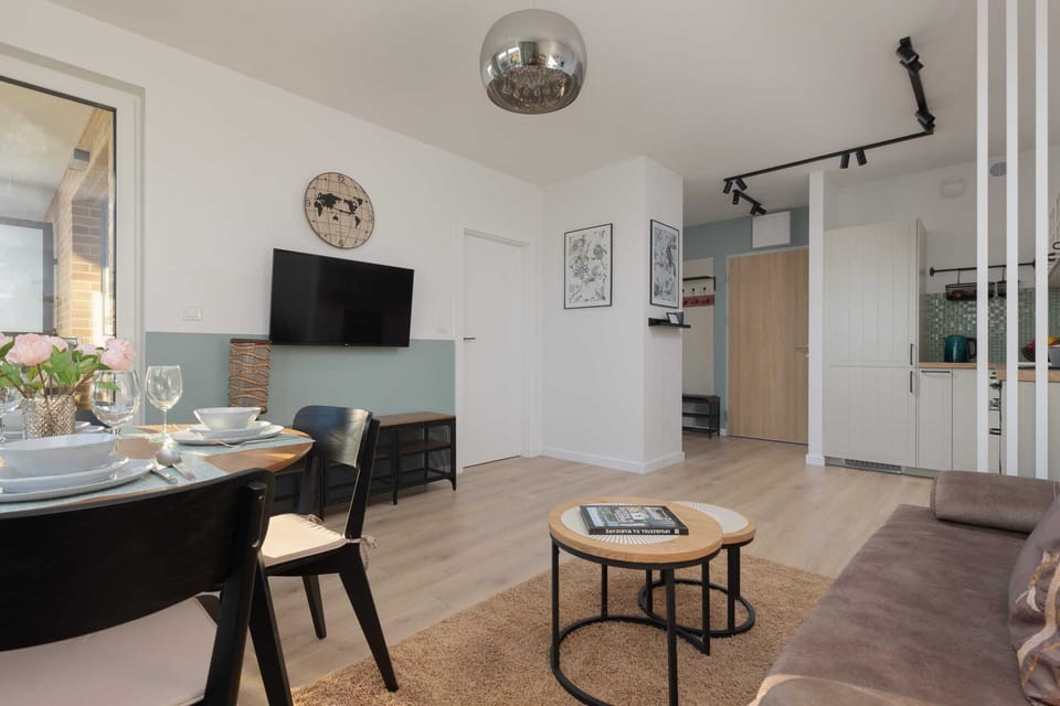 A cozy living space featuring a comfortable sofa, coffee table, and a TV unit with large windows leading to the balcony.

