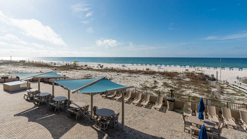 Outdoor pool and grilling area with tables and loungers, perfect for soaking up the sun and relaxing by the water