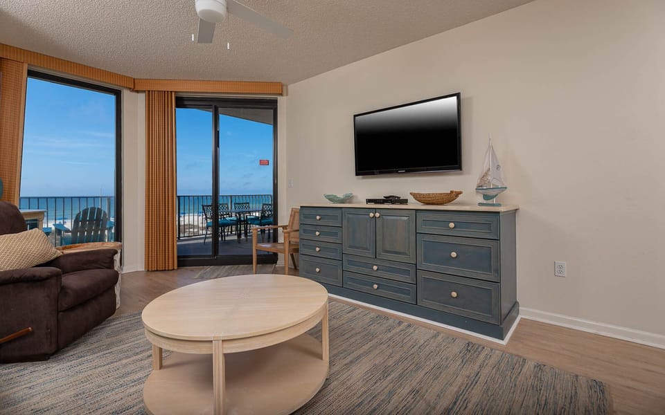 Unwind in the inviting living area with a cozy couch with queen sleeper, flat-screen TV, and stunningbeach views