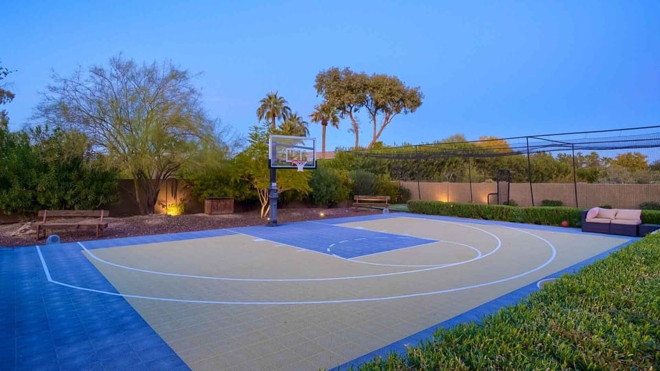 Half court basketball next to the batting cage w/ spectator seating & greenery