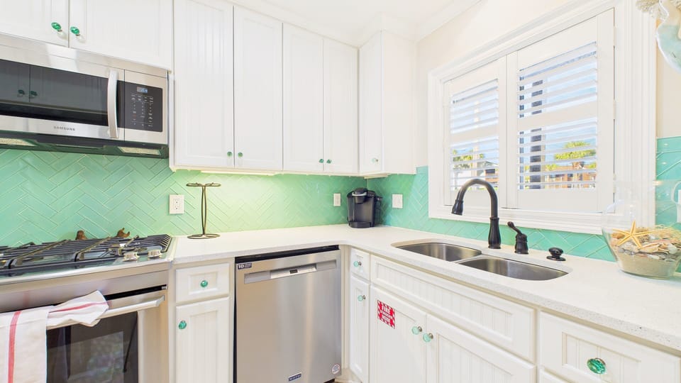 Your bright kitchen features modern appliances and charming mint green accents, perfect for preparing meals with coastal flair.