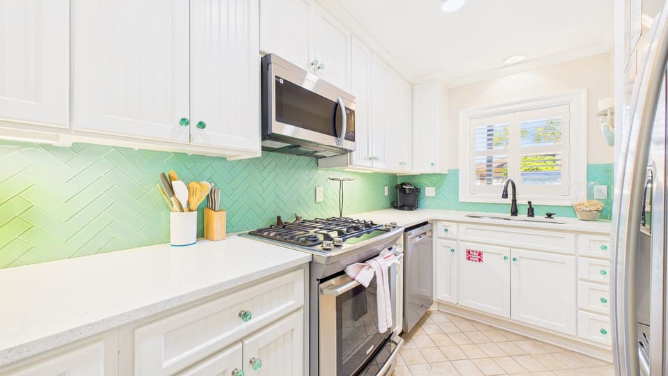 Your bright, fully-equipped kitchen features cheerful mint backsplash and modern appliances for preparing memorable meals during your stay.