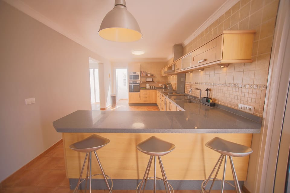 Modern kitchen with electric stove, dishwasher, knife block, and breakfast bar