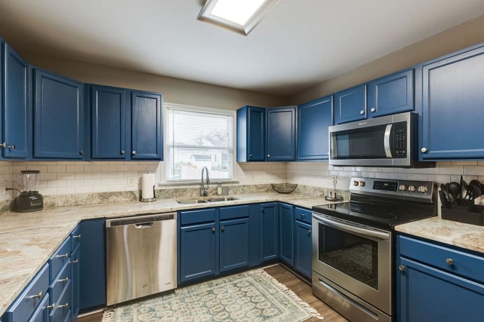 Fully stocked with all your cooking essentials, featuring a microwave, dishwasher, and a double-basin sink with a  window view—everything you need to feel at home.
