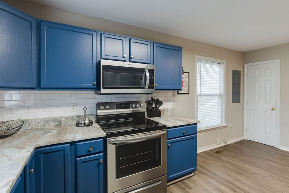 Fully stocked with all your cooking essentials, featuring a microwave, dishwasher, and a double-basin sink with a  window view—everything you need to feel at home.