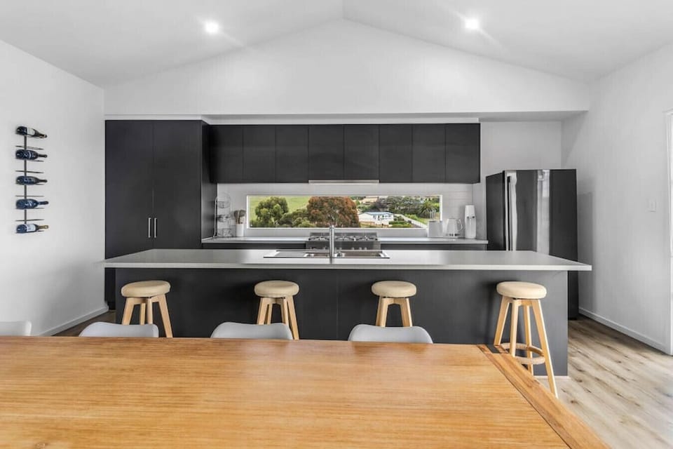 The kitchen area seamlessly blends functionality and style, with a sleek stool bar perfect for casual dining and a stunning view of the surrounding nature.