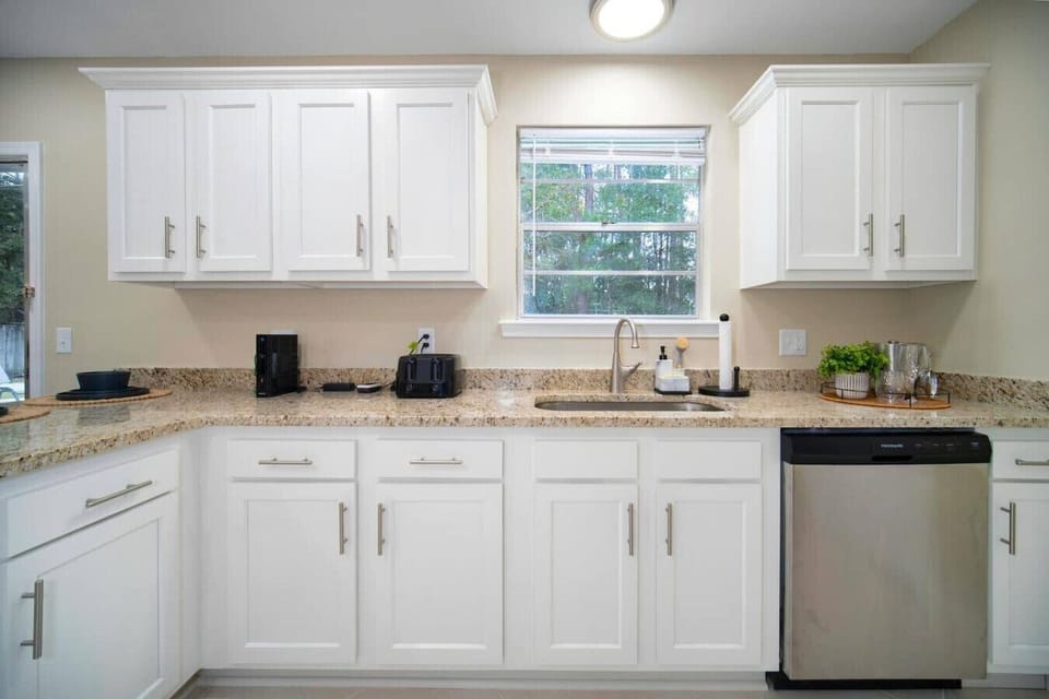 Bright and functional kitchen with sleek white cabinetry, a spacious granite countertop, and modern appliances, creating a clean and inviting space.