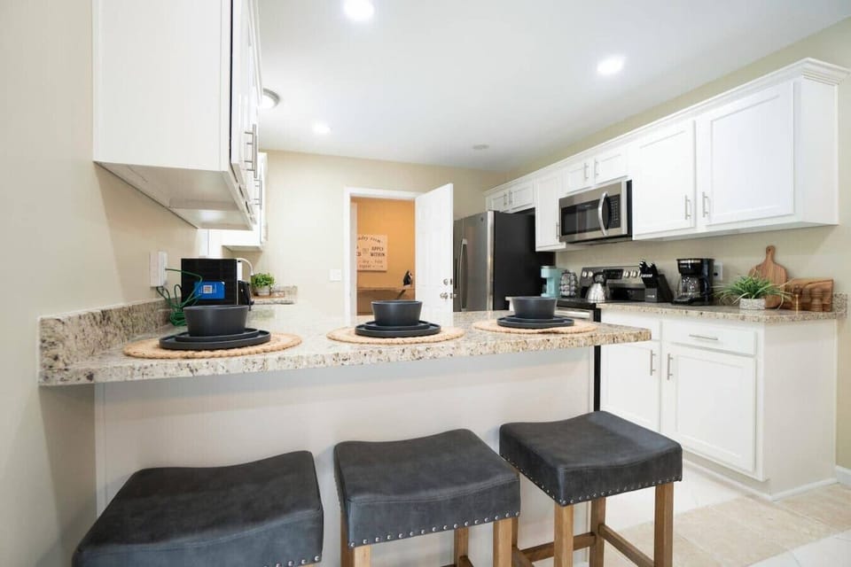 Modern kitchen with a stylish granite countertop, sleek appliances, and cozy bar seating, perfect for preparing and enjoying meals.