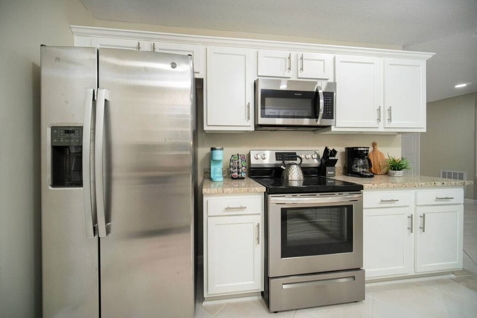 Modern kitchen featuring stainless steel appliances, including a refrigerator, stove, microwave, and coffee maker, with a granite countertop for an elegant touch.