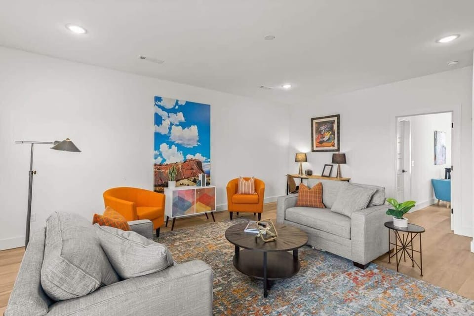 Unwind in a bright living room with curated art, comfy seating, & a modern coffee table—perfect for gatherings or quiet nights.