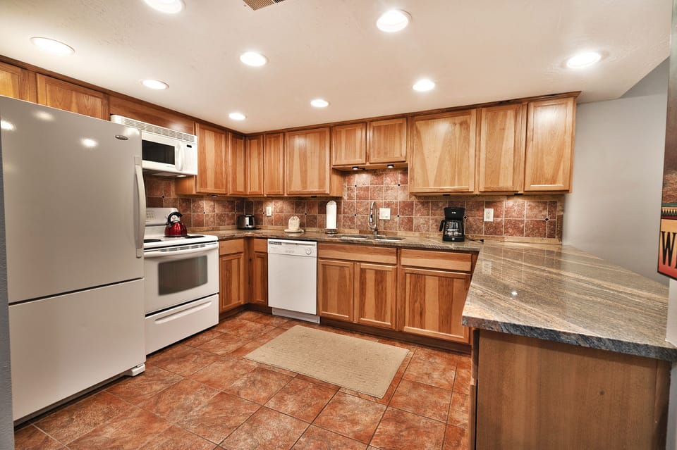 - Fully equipped kitchen with modern appliances  
- Ample counter space for cooking and preparing meals  
- Warm wood cabinetry with tiled backsplash design