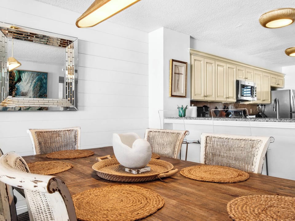 Gather around your beautifully appointed dining table for memorable meals, with elegant wicker placemats and a stunning ocean-inspired mirror creating the perfect atmosphere.