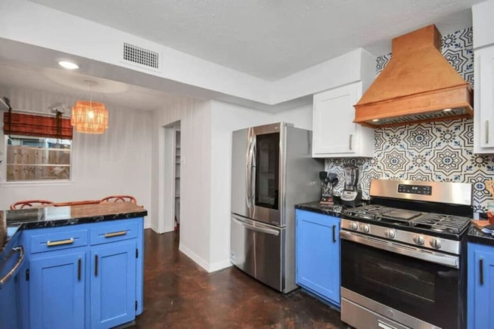 Colorful, fully equipped kitchen with modern appliances, bold tile backsplash, and vibrant cabinetry.