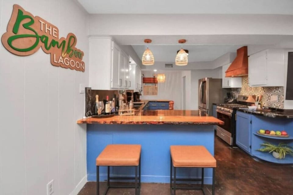 Chic kitchen bar with custom “Bamboo Lagoon” sign, stylish lighting, and bold blue cabinetry—ideal for casual sips or morning brews.