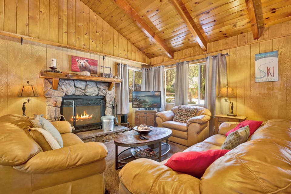 Cozy mountain living room with a stone fireplace, comfy seating, and smart TV—perfect for relaxing evenings, movie nights, and warm cabin vibes after outdoor adventures.