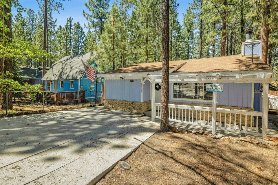 Welcoming cabin entry surrounded by towering pine trees, offering fresh mountain air and a peaceful forest setting—the perfect first impression for your Big Bear Lake getaway.