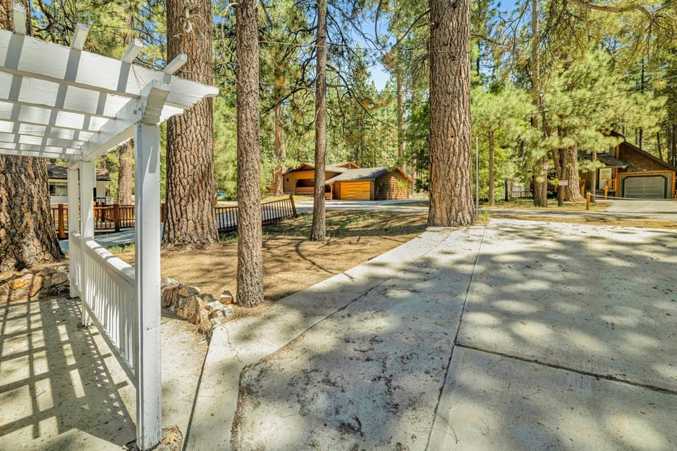 Welcoming cabin entry surrounded by towering pine trees, offering fresh mountain air and a peaceful forest setting—the perfect first impression for your Big Bear Lake getaway.