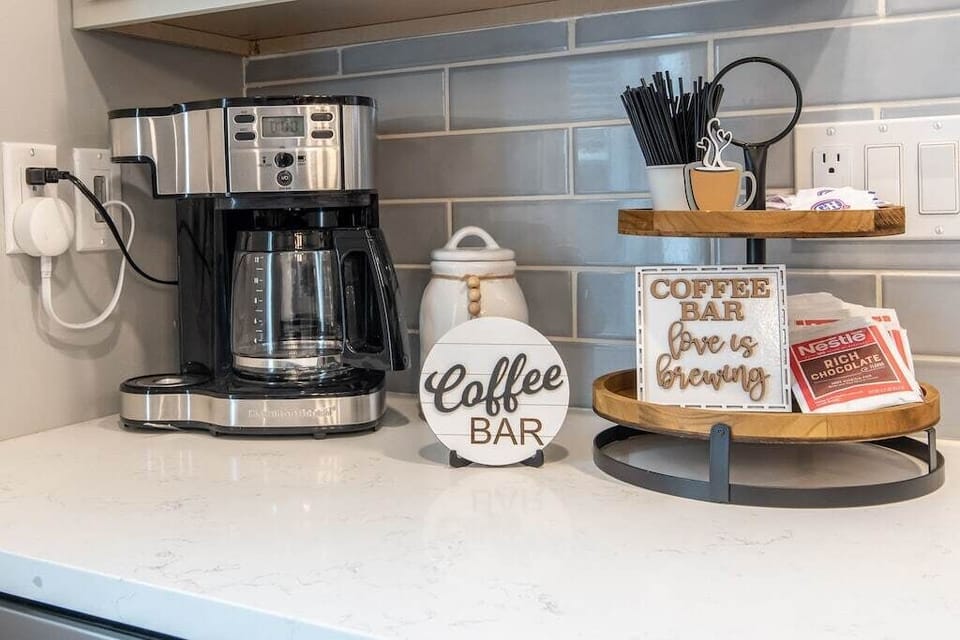 Lower Kitchen coffee bar- Hamilton beach duo coffee pot with hot chocolate, creamers, sugar, coffee, tea, and stir sticks 