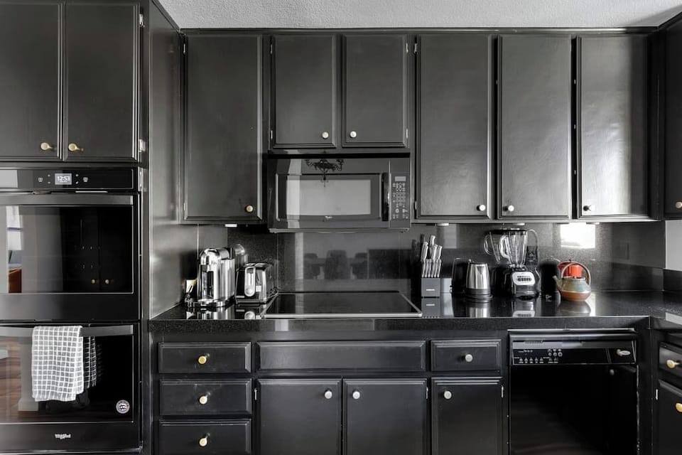 Kitchen wall with double wall oven, ceramic cooktop, over-range microwave, and full appliance lineup including espresso machine and blender