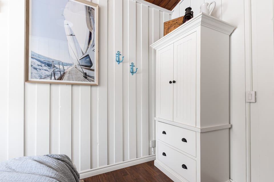 Second bedroom with armoire, side table & window with blinds