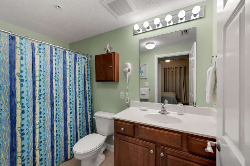 Bathroom with a shower curtain and wooden vanity under bright lighting