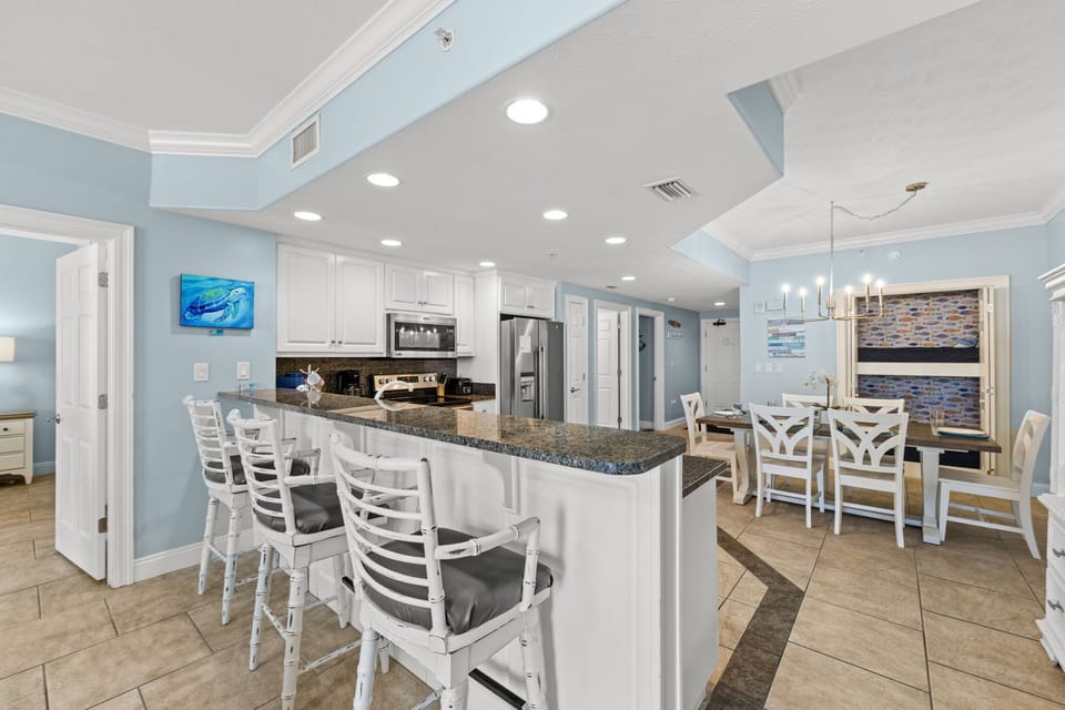 Modern kitchen with granite countertops and a breakfast bar opening to the dining area.