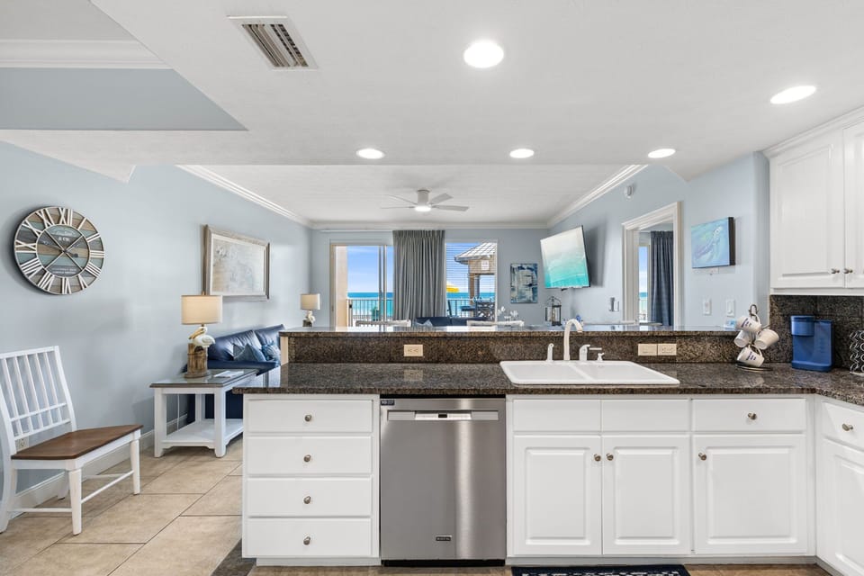 Open kitchen with granite countertops and a view of the living area and balcony.